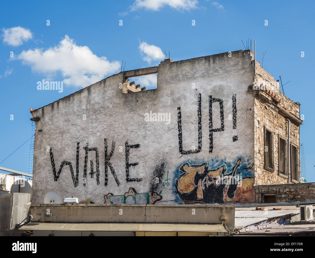 'Wake up' Street art or graffiti murial painted onto the side of a building in Plaka Athens Stock Photo
