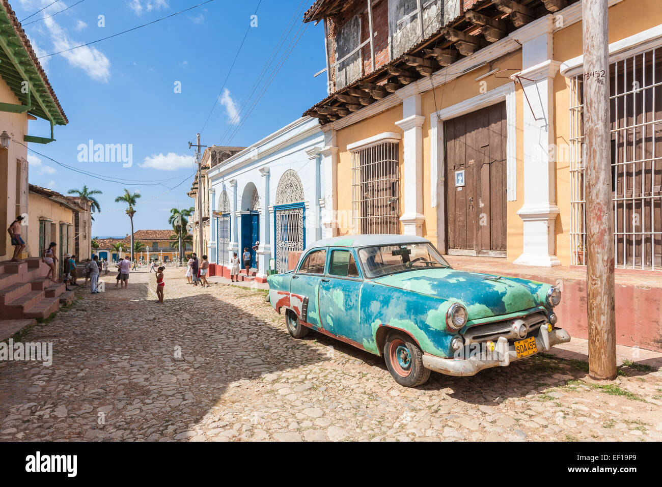 View of typical battered, old, rusty green vintage American car parked in a cobbled street in downtown Trinidad, Cuba on a sunny day with blue sky Stock Photo