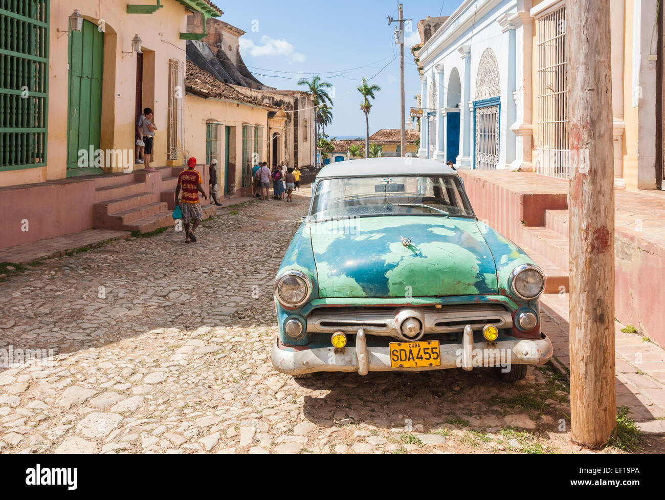 View of typical battered, old, rusty green vintage American car parked in a cobbled street in downtown Trinidad, Cuba on a sunny day with blue sky Stock Photo