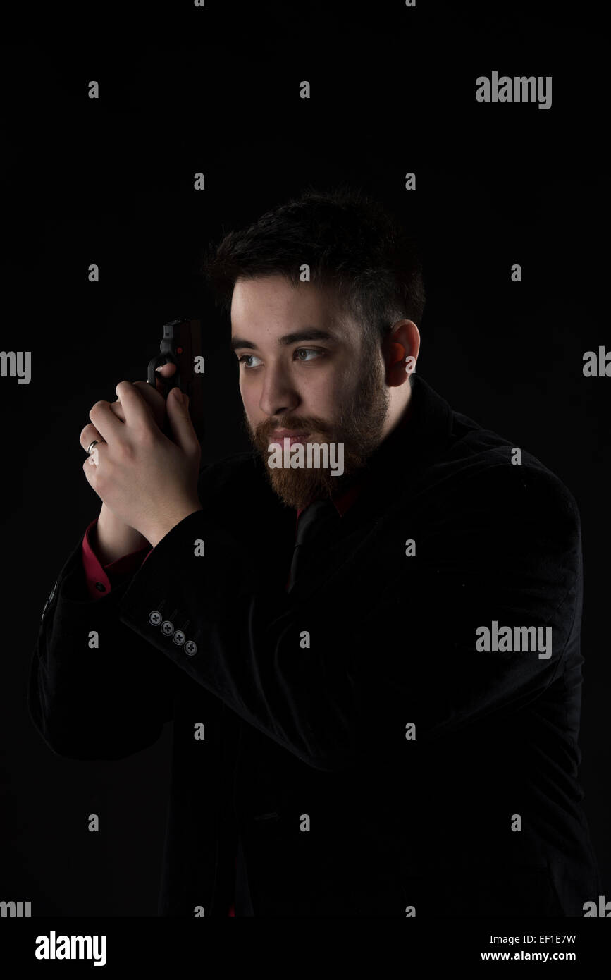 Goatee Man in Black Suit Holding Weapon Stock Photo