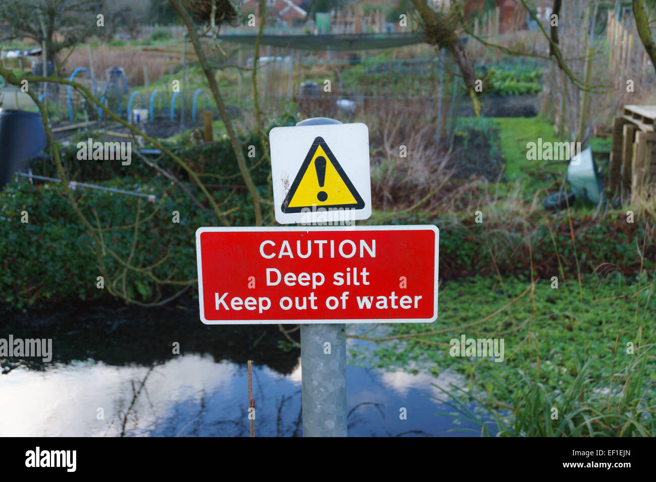Sign warning of deep silt and to keep out of water in Winchester, UK next to the River Itchen Stock Photo