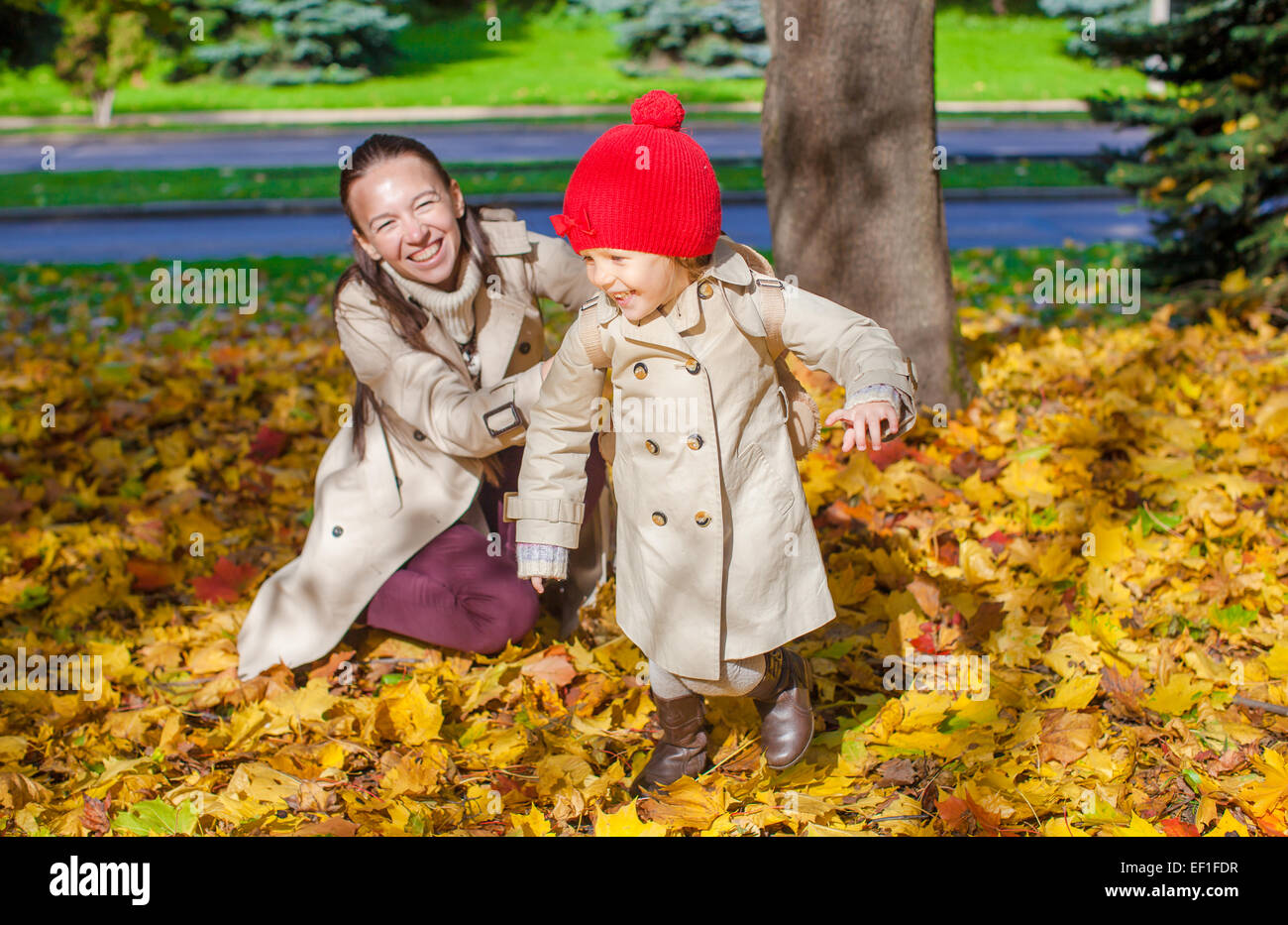 Little girl and young mom in yellow autumn park on sunny day Stock ...