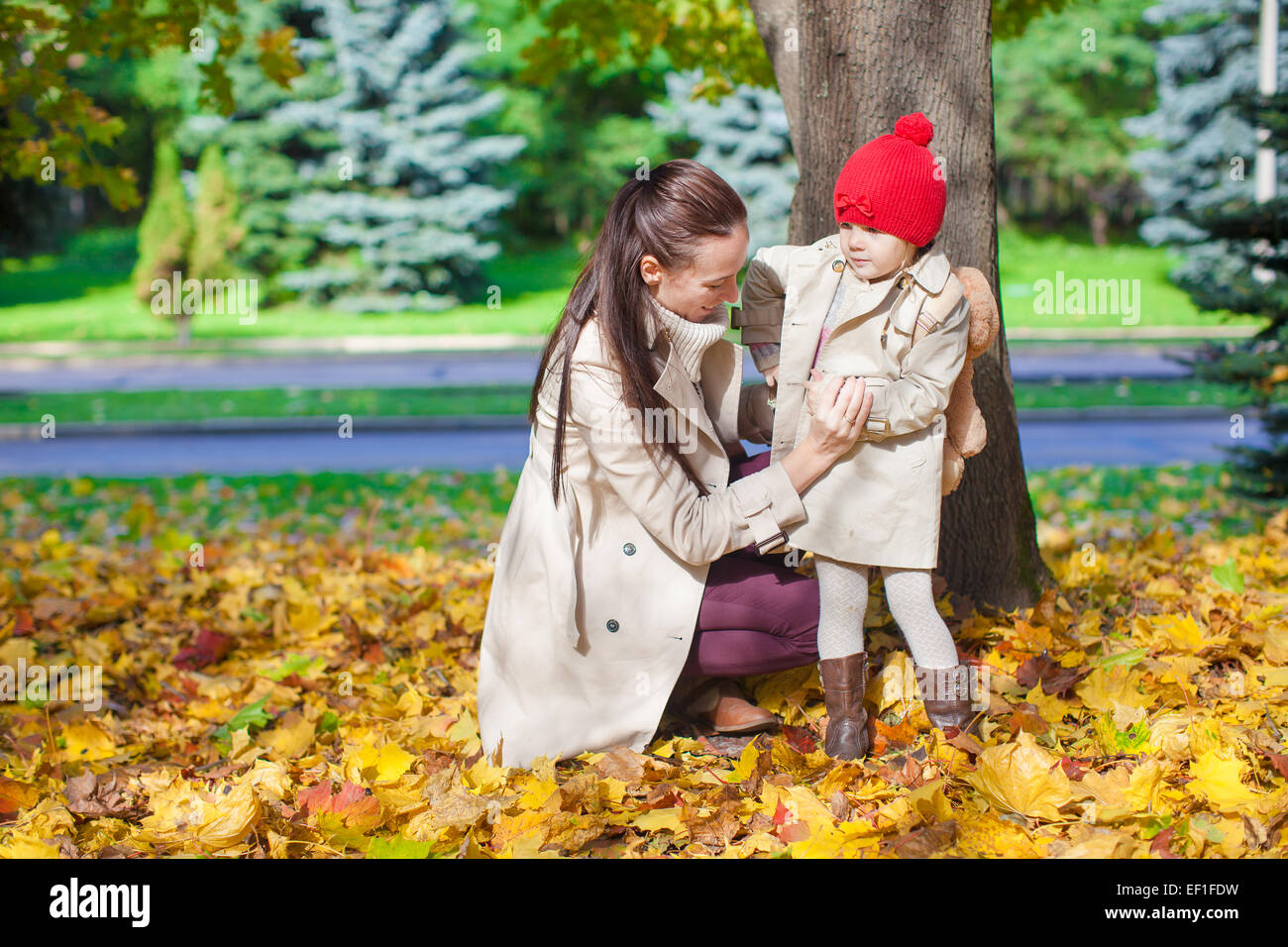 Little girl and young mom in yellow autumn park on sunny day Stock ...
