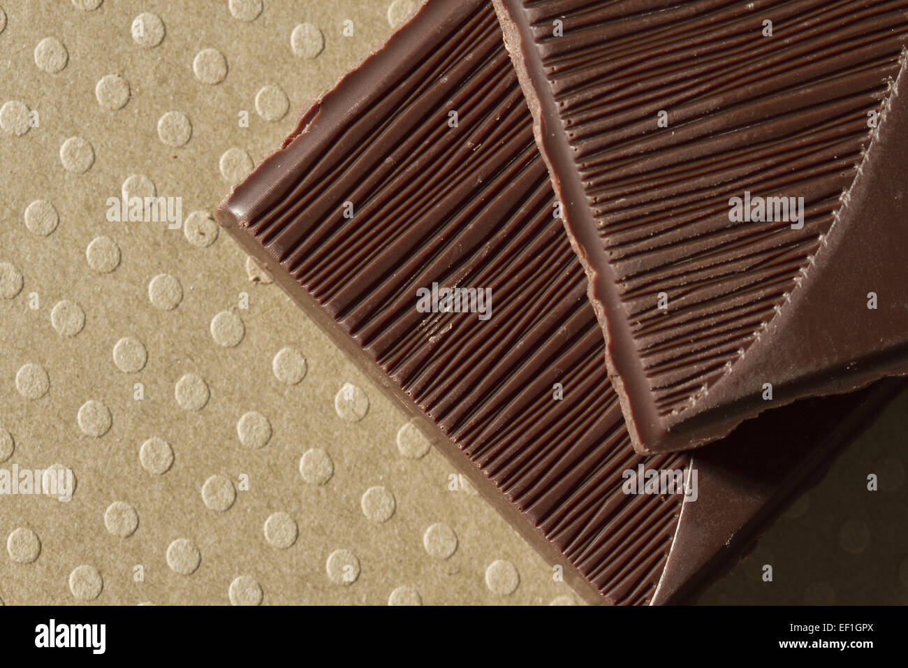 Close-up of dark chocolate piece on dotted ground. Stock Photo