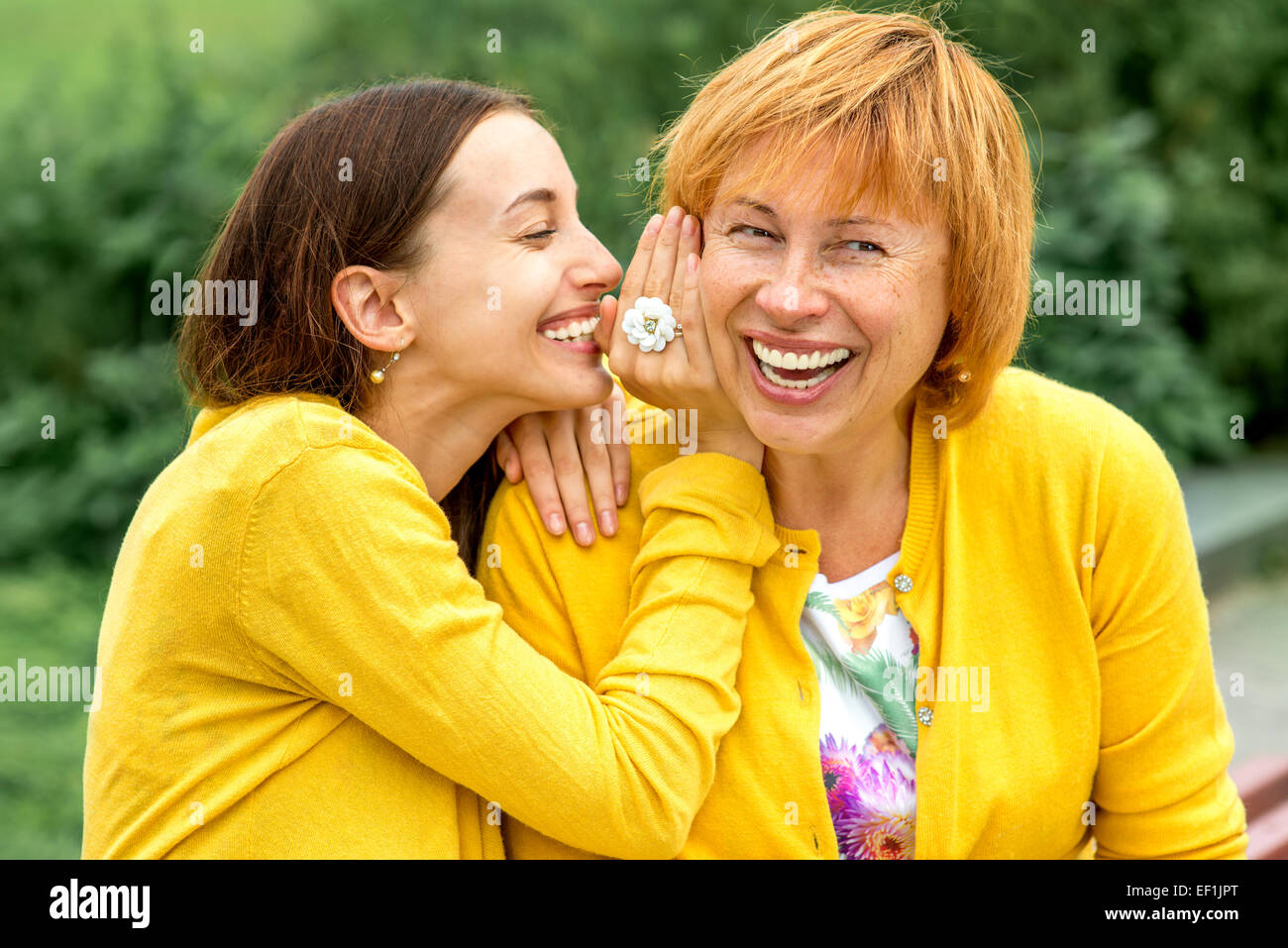 Daughter whispering something to her mother in the park Stock Photo