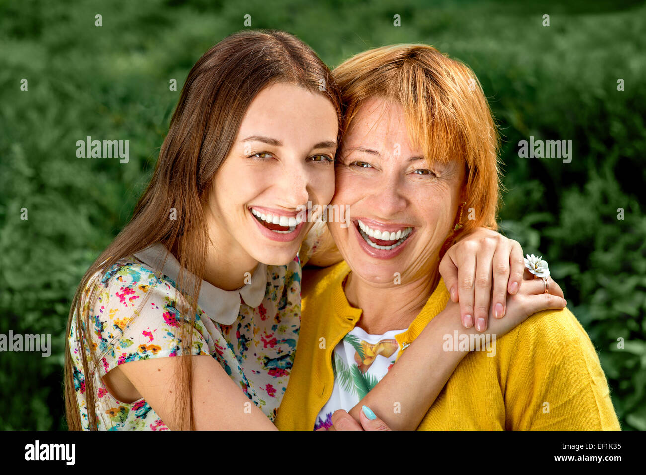 Mother with her daughter smiling and hugging dressed in yellow in the park Stock Photo
