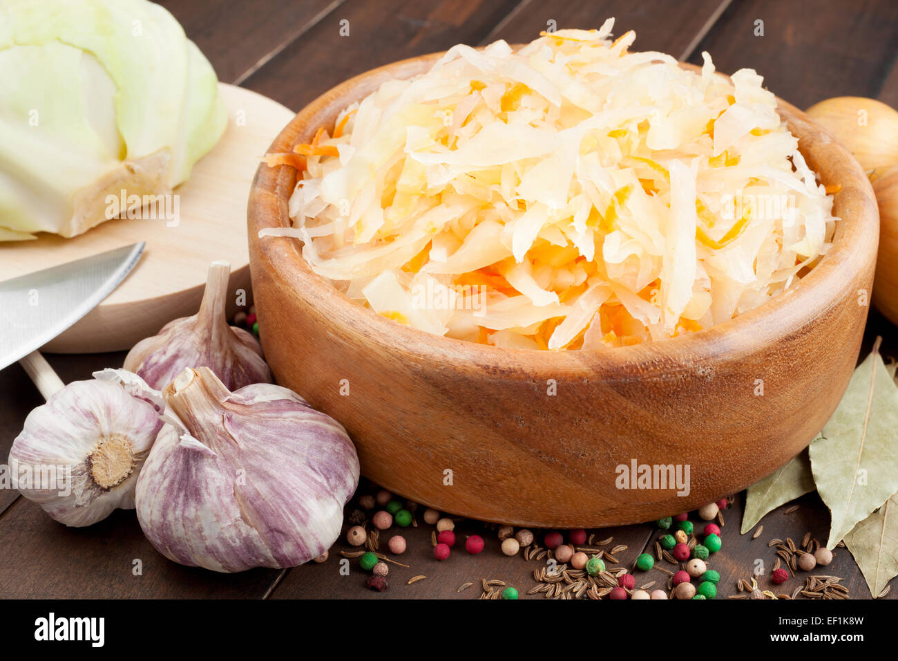 Sauerkraut with carrot in wooden bowl, garlic, spices, cabbage on a cutting board Stock Photo
