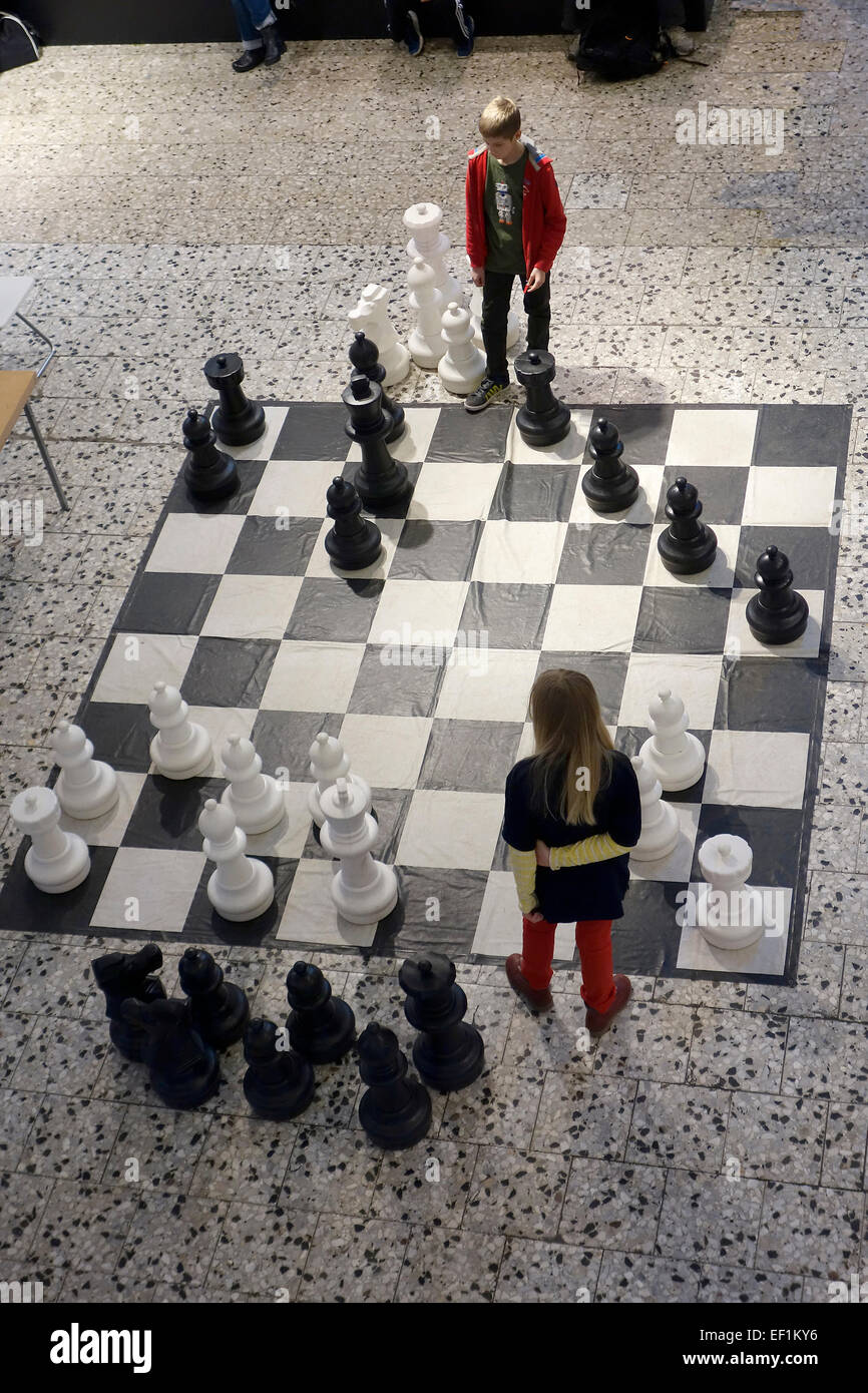 10 years old girl and boy play chess in public with large garden plastic chess set.  Nordstan, Göteborg, Sweden Stock Photo