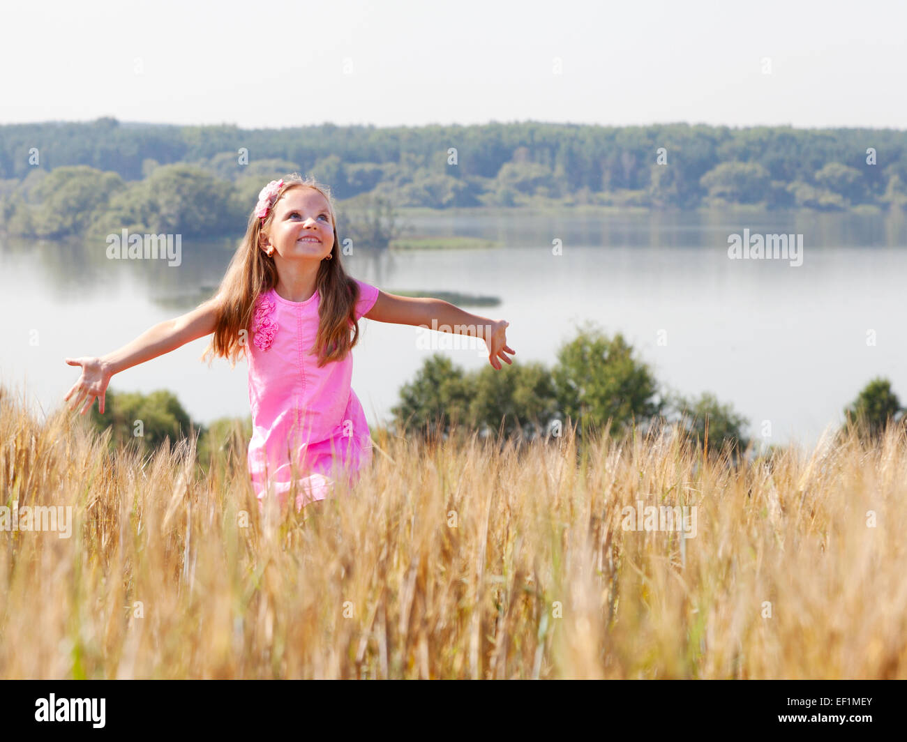 happy girl in summer field near lake on a sunny day Stock Photo