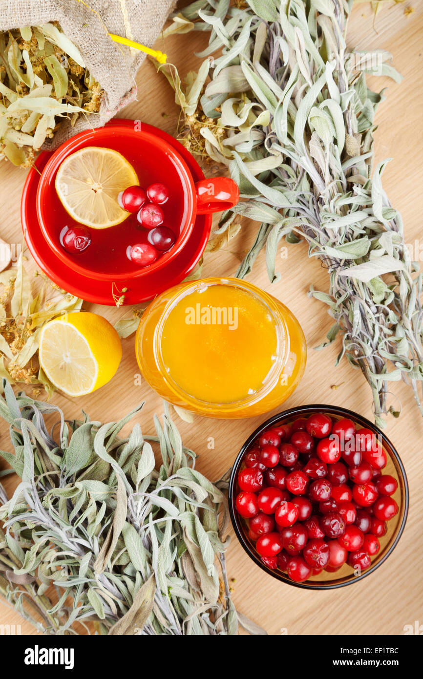cranberries, jar with honey, fruit tea cup, healing herbs and lemon. Top view. Stock Photo