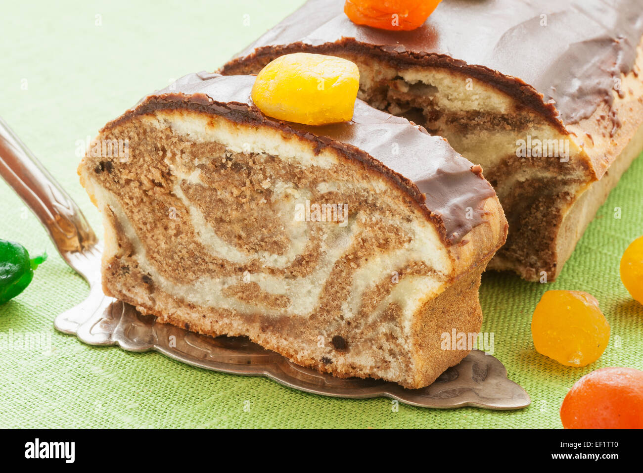 Marble pound cake with chocolate glaze and caramelized fruits on kitchen table Stock Photo