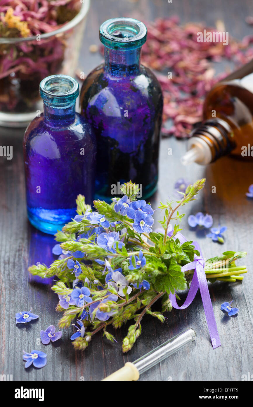 glass bottle of essential oil and blue healing flowers on wooden table Stock Photo