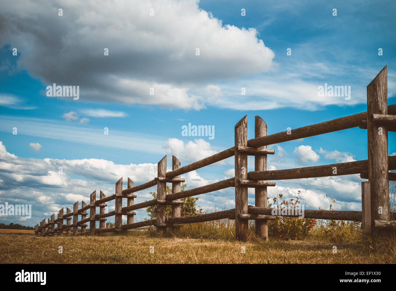 wooden rustic fence in village and blue sky with clouds Stock Photo