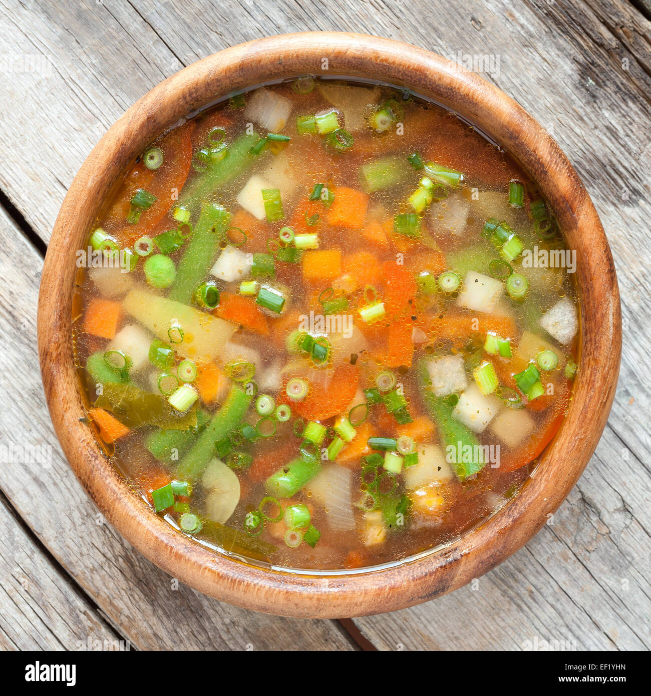 Close up view of a wooden table with a fresh, ready-to-eat homemade  vegetable soup. Stock Photo by lucigerma