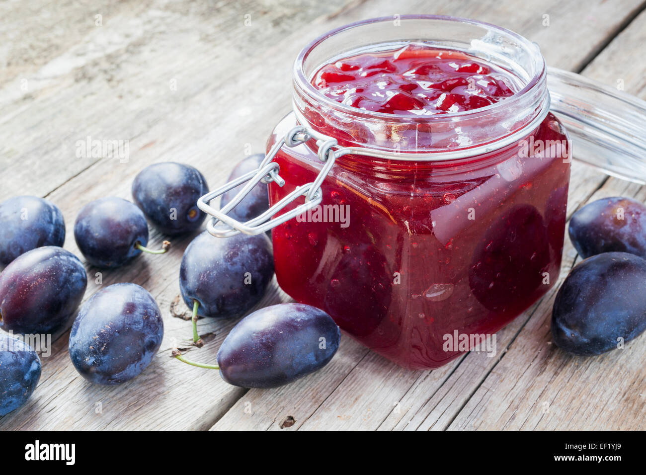 plums and jar of jam on table Stock Photo