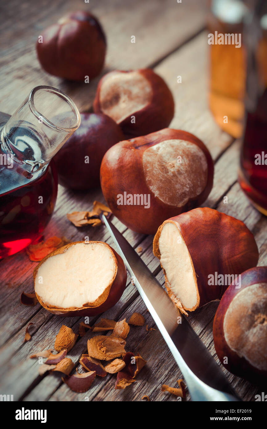 Chestnuts and bottle with tincture on wooden rustic table Stock Photo