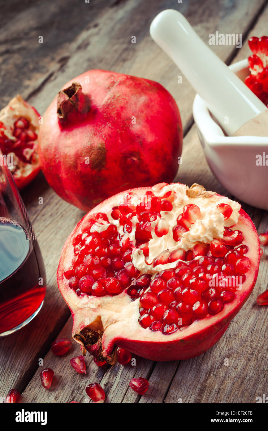 Pomegranate, juice in glass, mortar and pestle on wooden rustic table Stock Photo