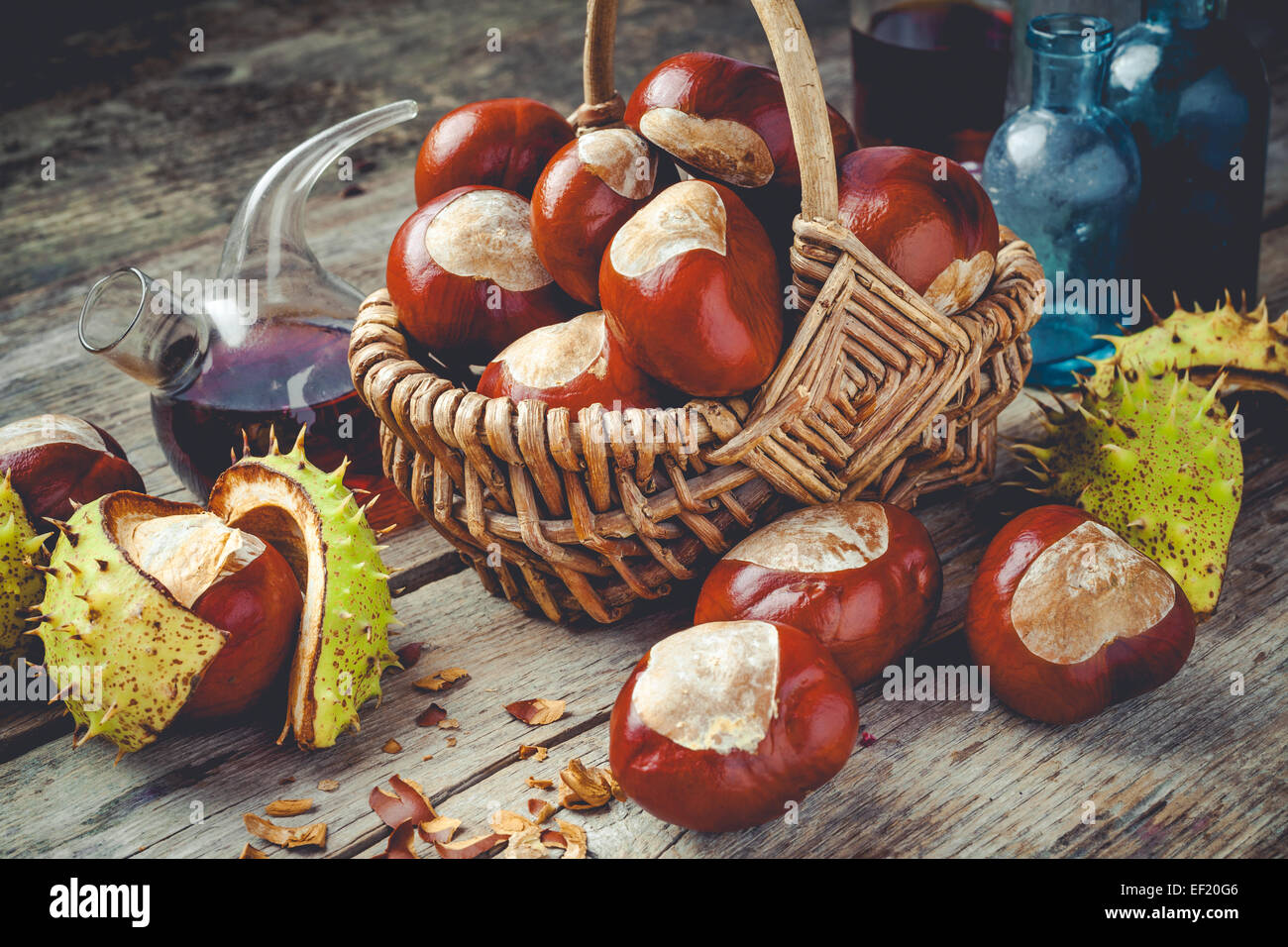 chestnuts in basket and vials with tincture on wooden table Stock Photo
