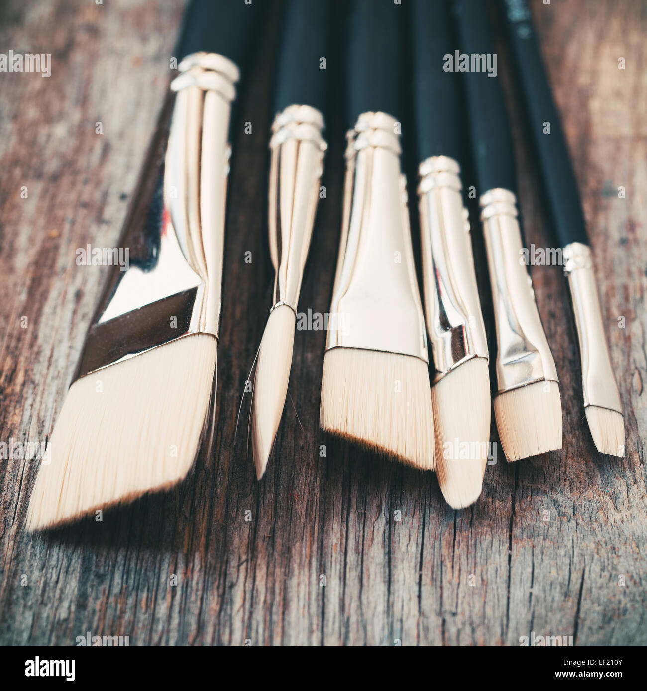 Set of artist paintbrushes closeup on old rustic wooden table. Stock Photo