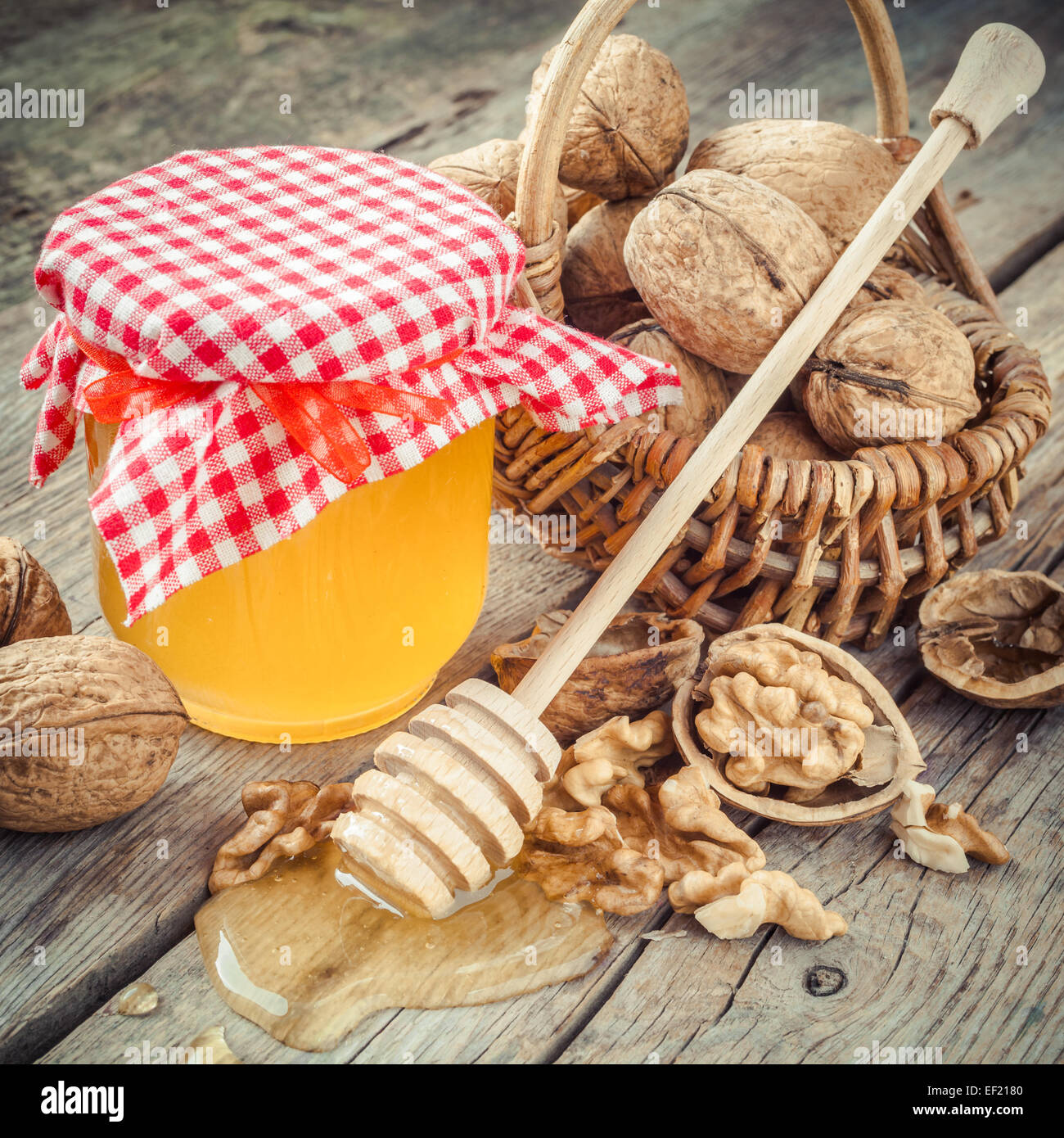 Honey in jar, walnut in basket and wooden dipper on old kitchen table Stock Photo