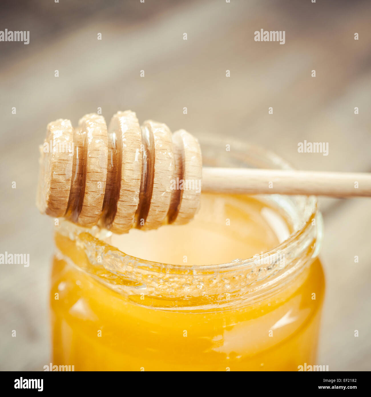 Honey in glass jar and wooden dipper close up Stock Photo