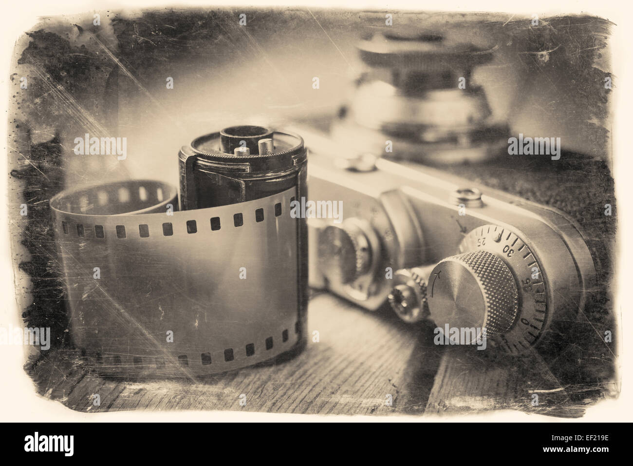 Old photo film roll and retro camera on desk. Vintage stylized photo. Stock Photo