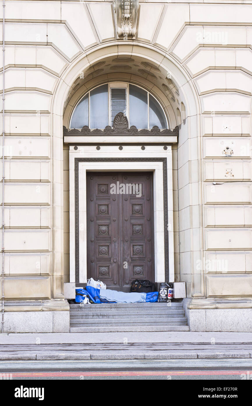 MANCHESTER, UK - JANUARY 14 2015: A homeless person sleeps under blankets in a doorway in Manchester, UK. Stock Photo