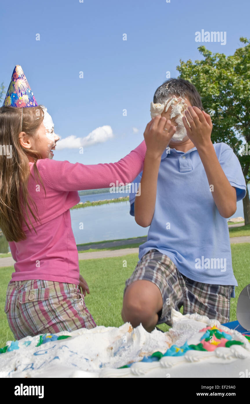 Girl putting cake on boy's face Stock Photo Alamy