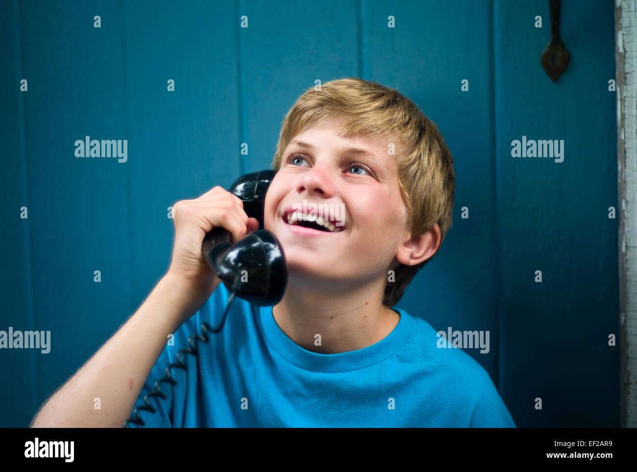 Child 10,11,12,13 laughing while talking on telephone, holding receiver Stock Photo