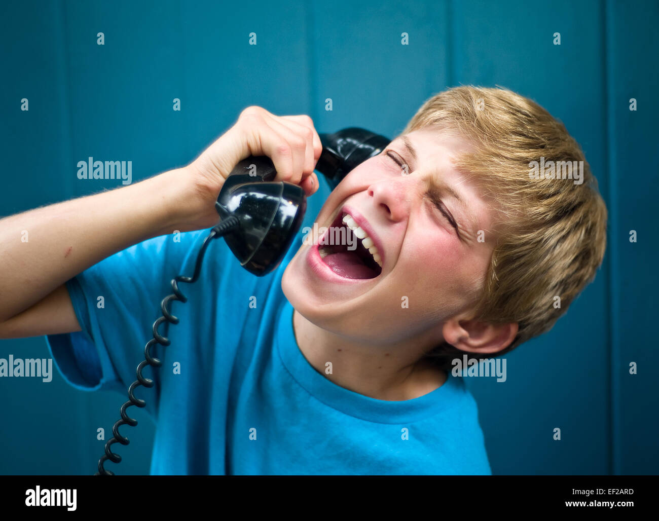 Child 10,11,12,13 laughing while talking on telephone, holding receiver Stock Photo