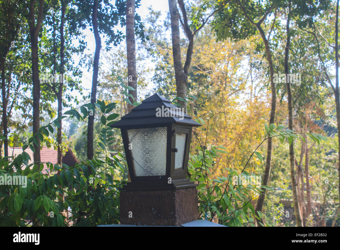 lantern on the log pole of wooden bench in garden Stock Photo