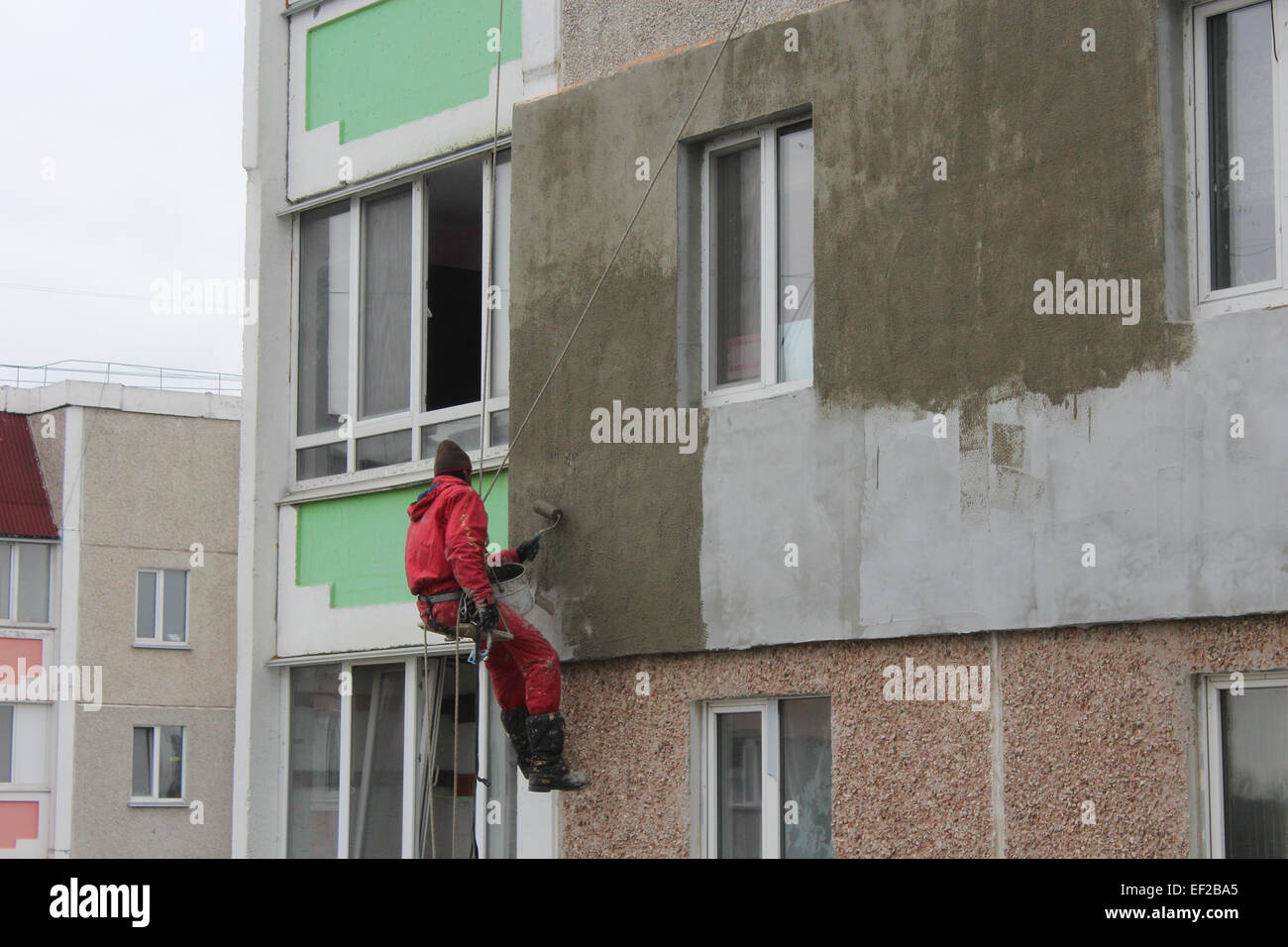 specialist carring out warming of many-storied building's wall on the height Stock Photo