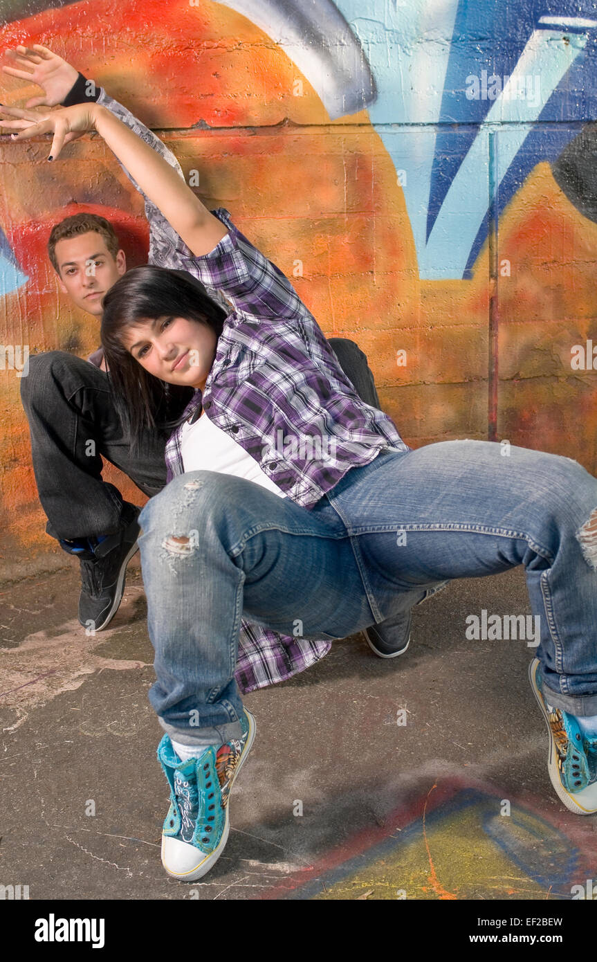 Two teenagers posed in front of a graffiti covered wall Stock Photo
