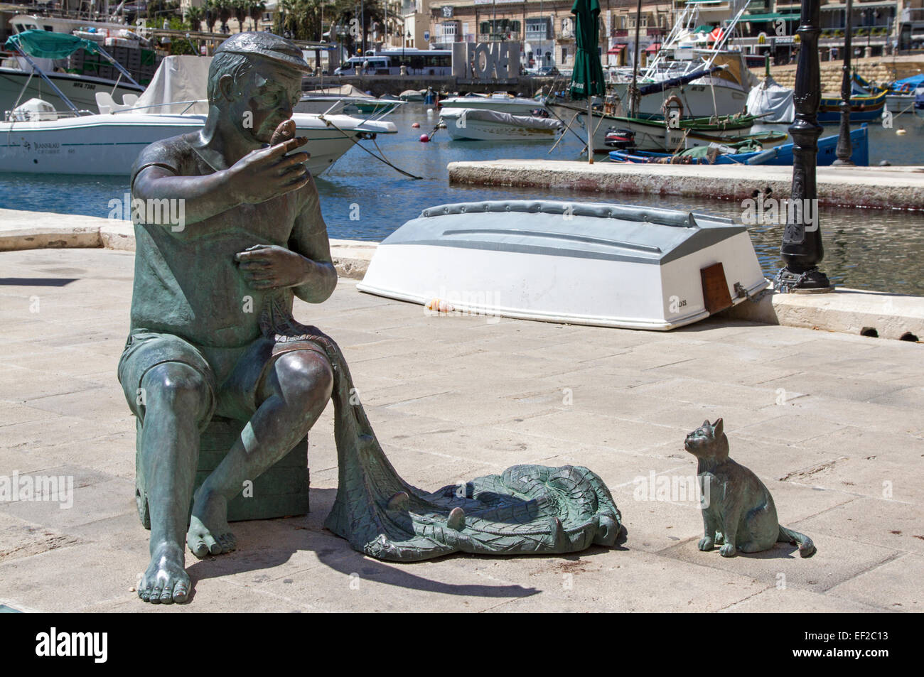 A statue of a fisherman with his nets and a cat waiting for fish on the harbour side at St. Julian's bay, Malta Stock Photo