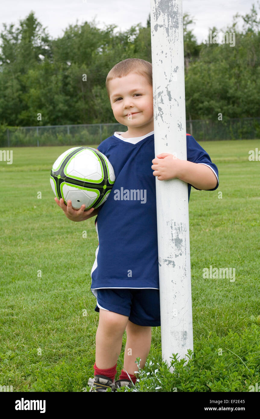 Young boy standing behind soccer goal post Stock Photo