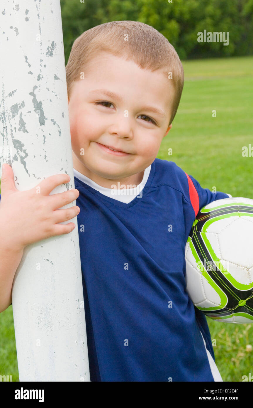 Young soccer player standing beside goal post Stock Photo