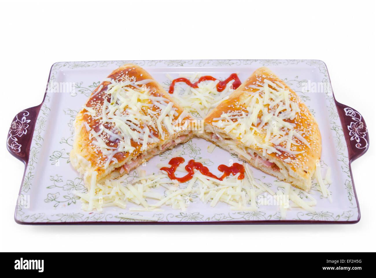 Stuffed pizza cut in half decorated with grated cheese on a plate, isolated on white background Stock Photo