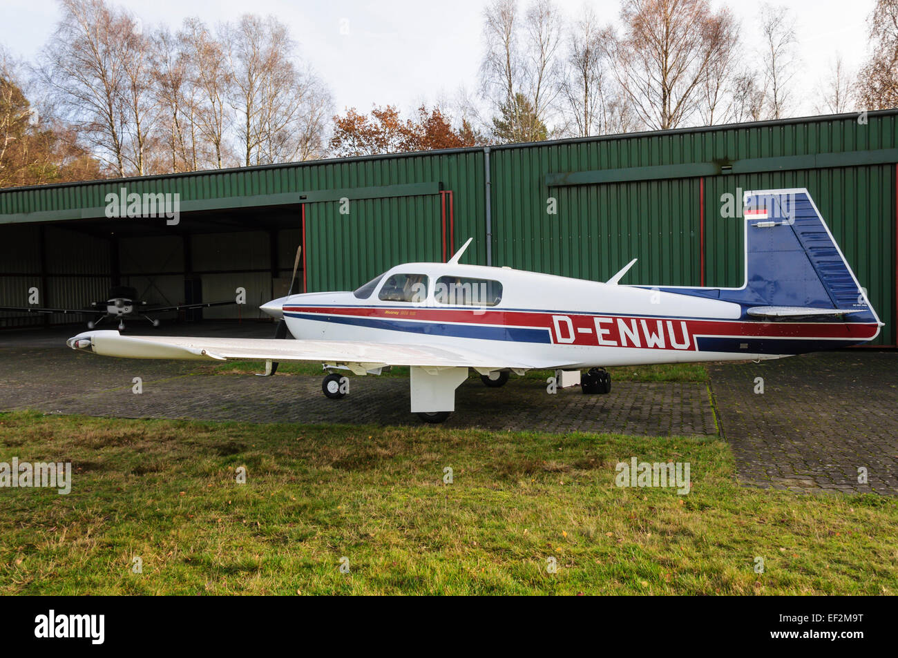 Private aircraft Mooney M20J '201' parked in front of green hangar in Celle, Germany Stock Photo