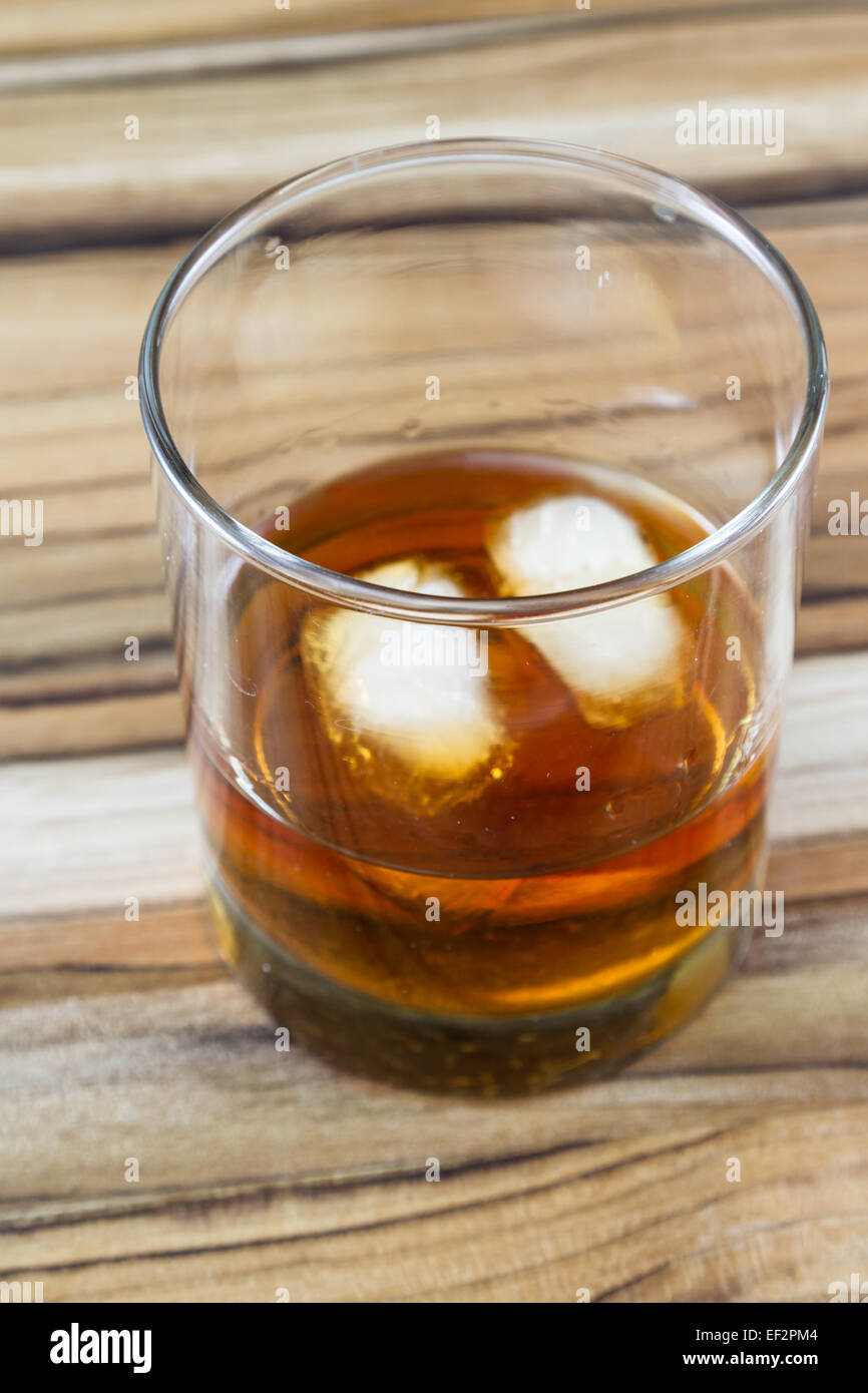 2 ice cubes floating in a glass with Kentucky straight Bourbon, served on a  wooden table Stock Photo - Alamy