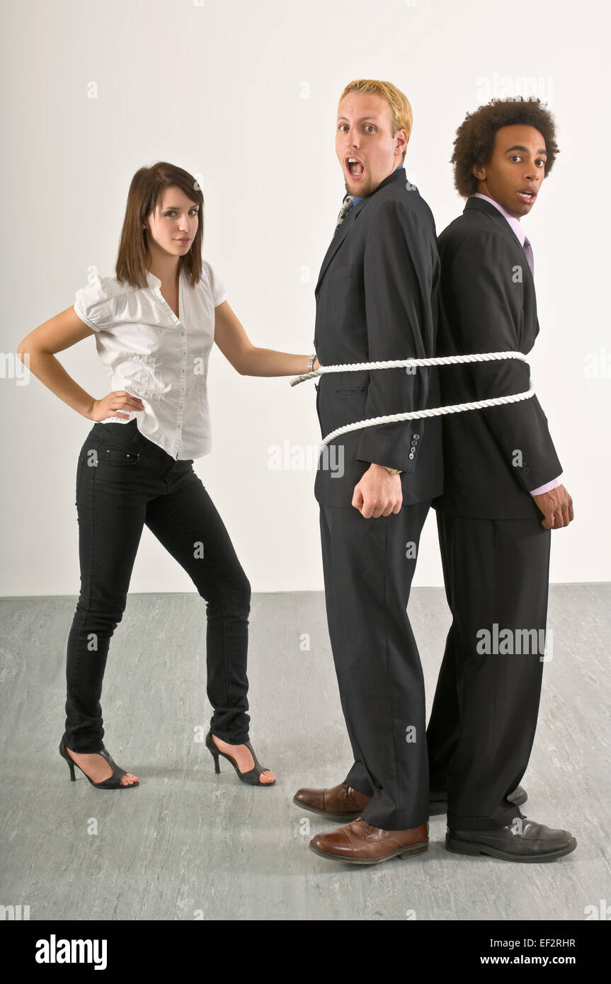 Woman tying two businessmen together with a rope Stock Photo