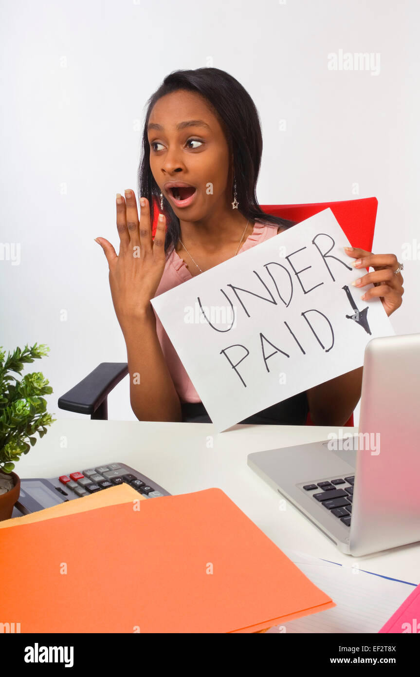 Underpaid businesswoman sitting at her desk Stock Photo