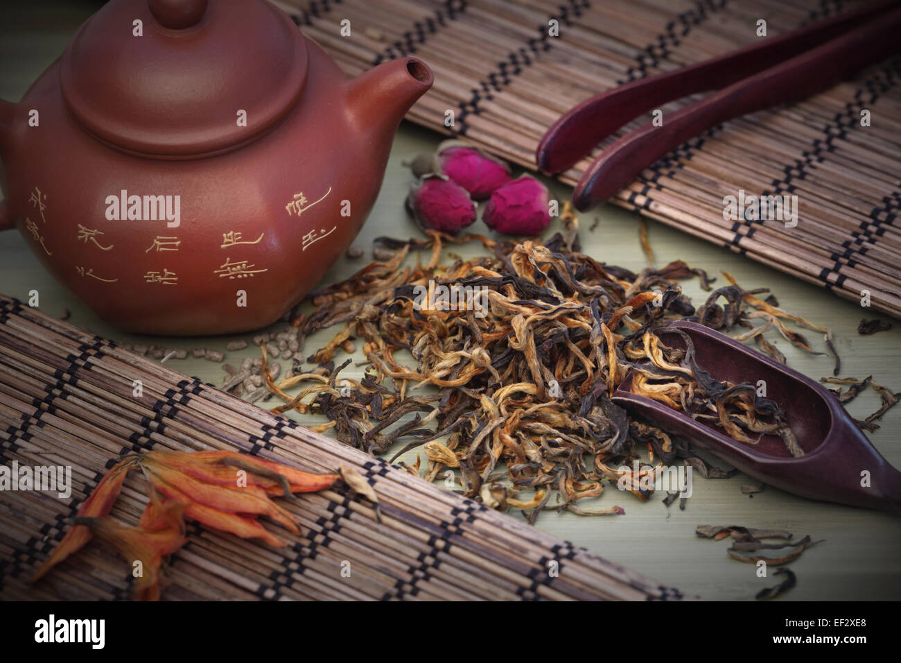 Dian Hong Mao Feng tea. Green tea leaves with clay teapot and wooden spoon on a tea table. Stock Photo