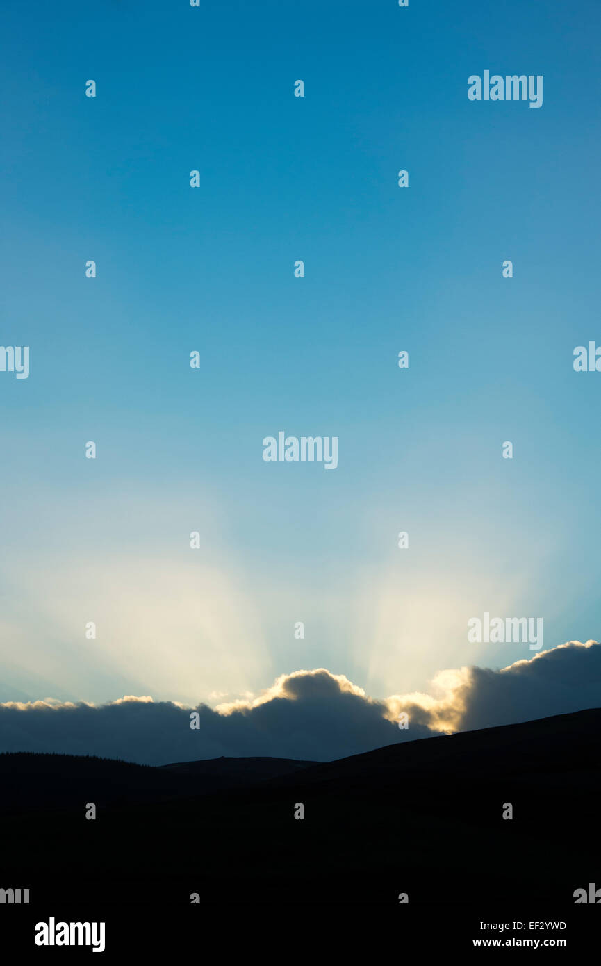 Sunset sun rays behind clouds in Scotland Stock Photo