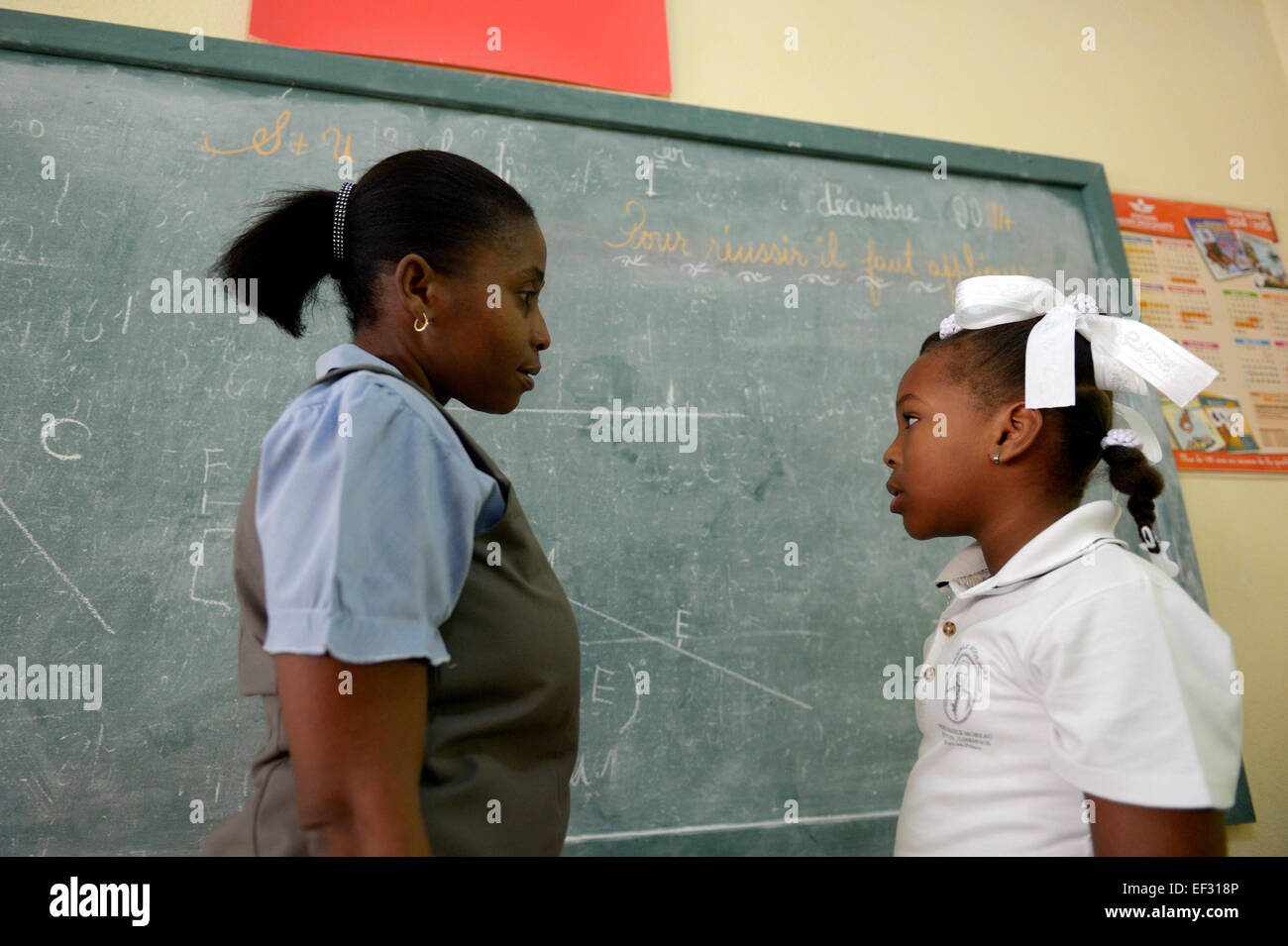 Schoolgirl speaking with her teacher, Basile Moreau Primary School, Carrefour, Port-au-Prince, Ouest Department, Haiti Stock Photo