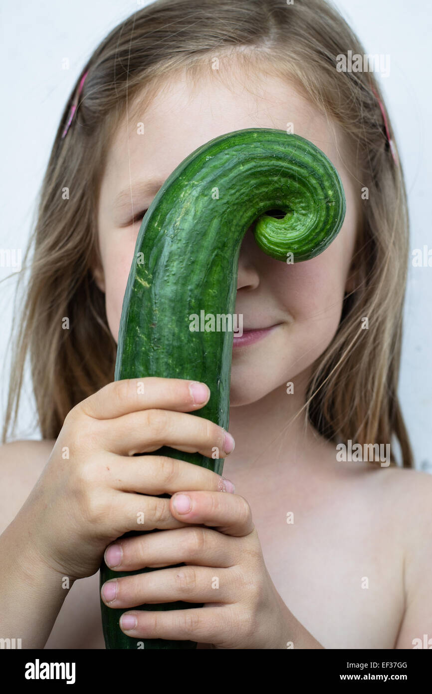 smiling girl holding a funny-shaped cucumber Stock Photo