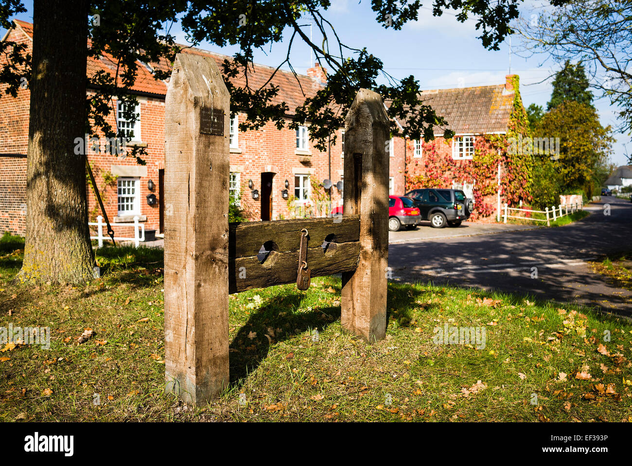 Old wooden stocks on village green in Keevil Wiltshire UK Stock Photo