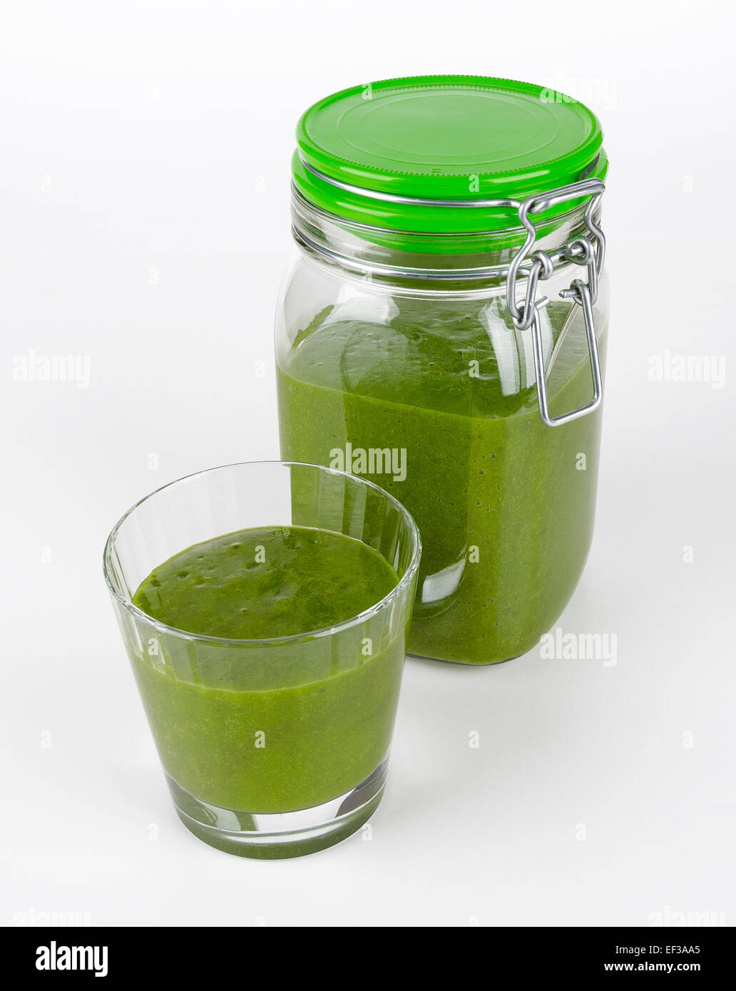 Green smoothie made of organic spinach, kale and fruits in a glass and in a closed jar. A raw, healthy, fresh and vegan beverage Stock Photo