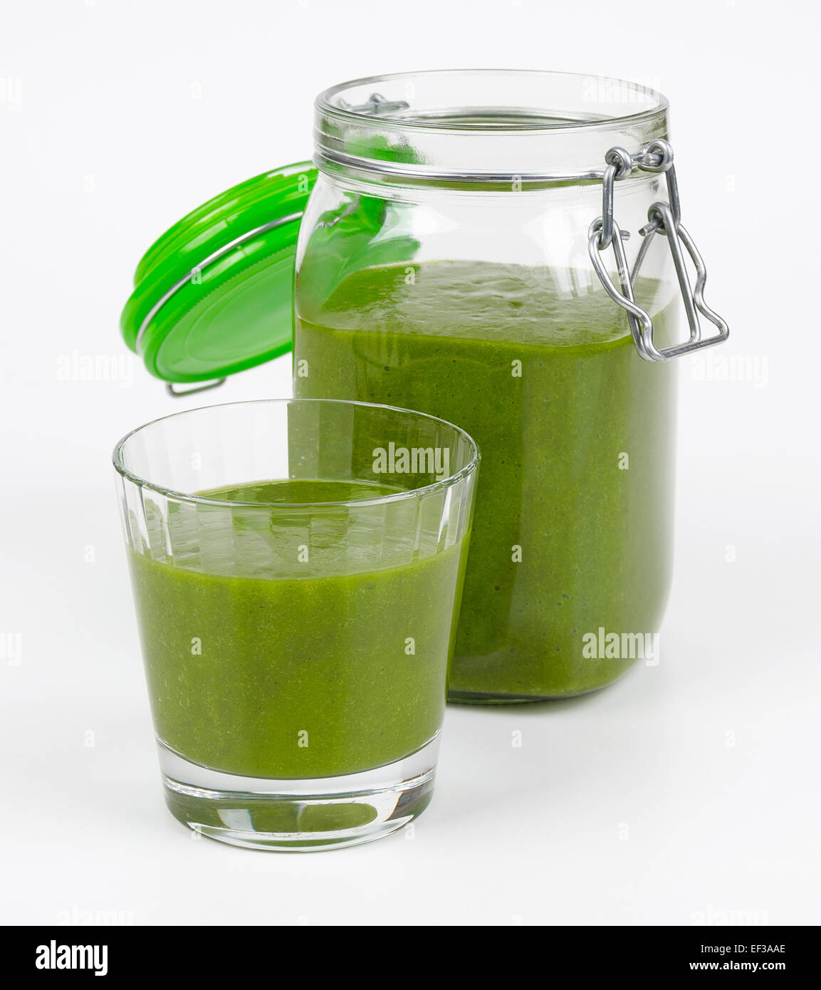 Green smoothie made of organic spinach, kale and fruits in a glass and in a open jar. A raw, healthy, fresh and vegan beverage. Stock Photo