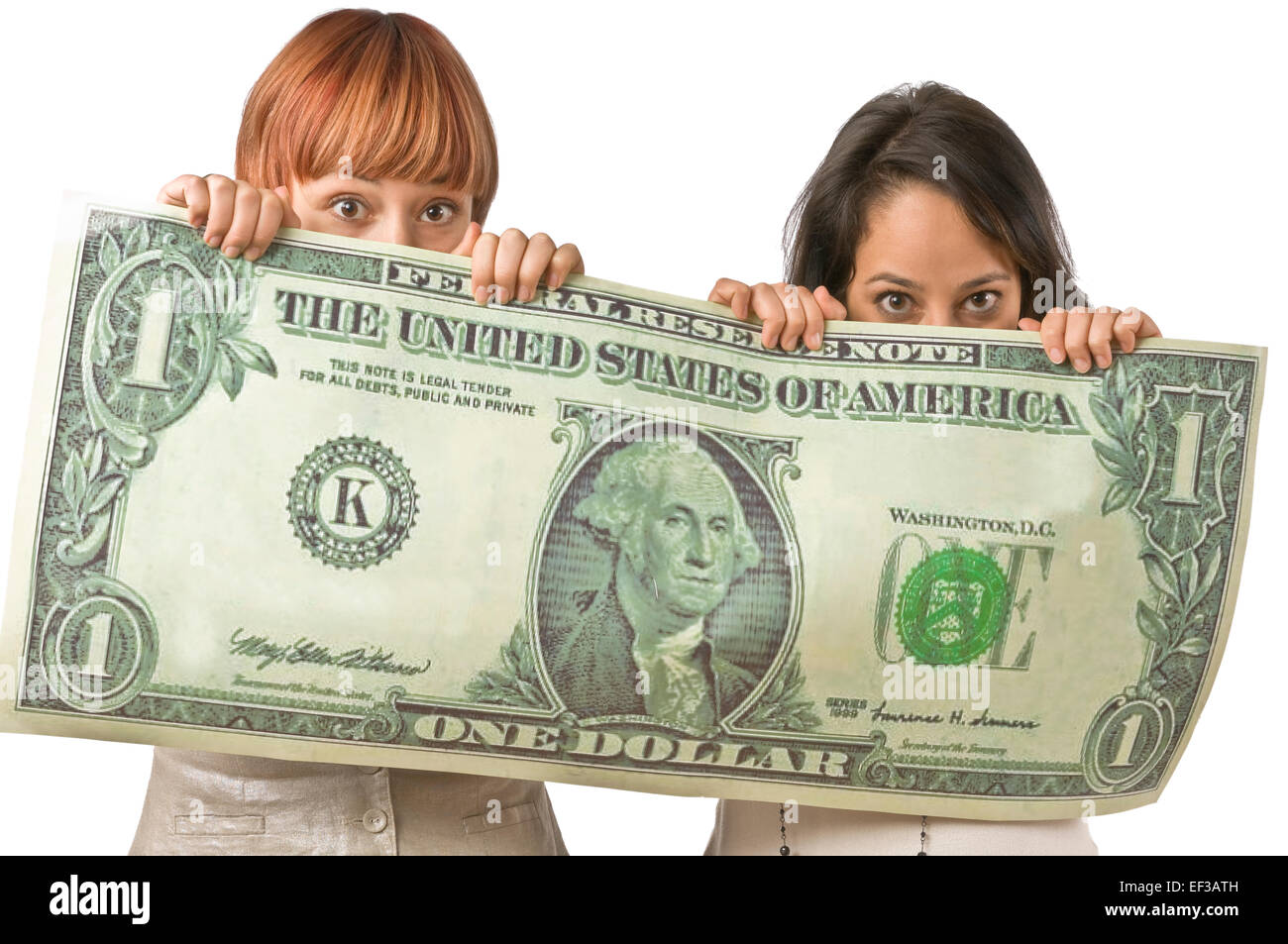 Two women peeking from behind oversized dollar bill Stock Photo