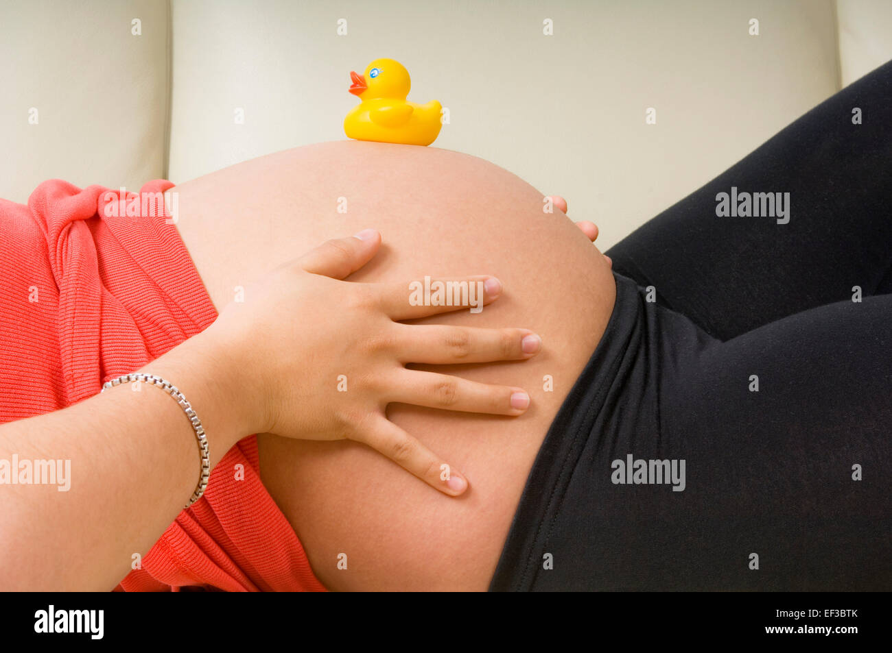 Rubber duck on a pregnant woman's belly Stock Photo